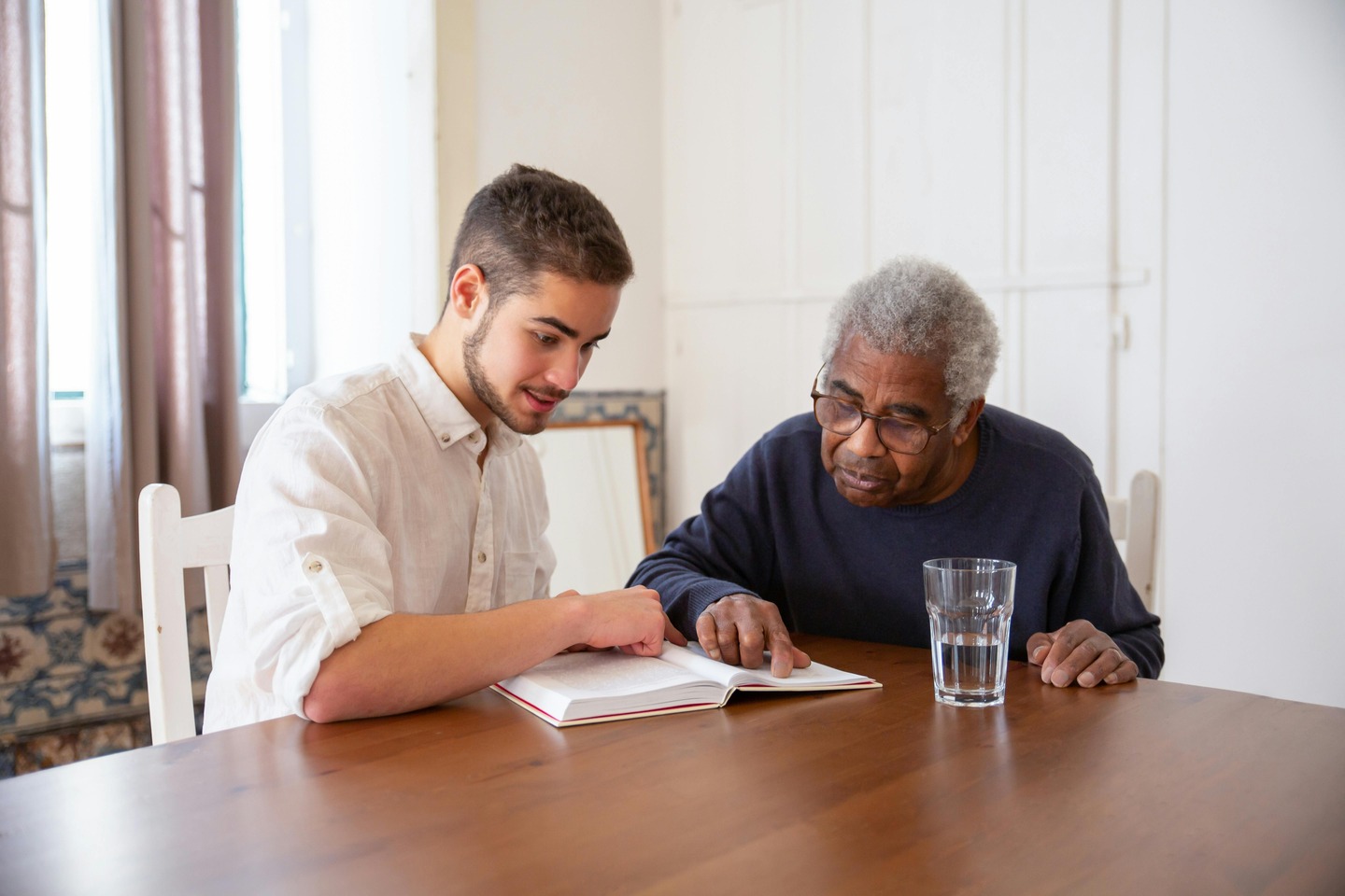 Caregiver reading a book with an elderly resident